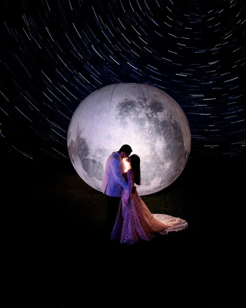 Couple embracing beneath a large moon-like disc and curved trails of light