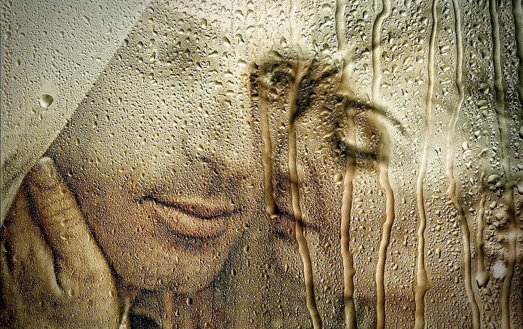 Retrato cercano de una pareja a través de un cristal cubierto de gotas de agua