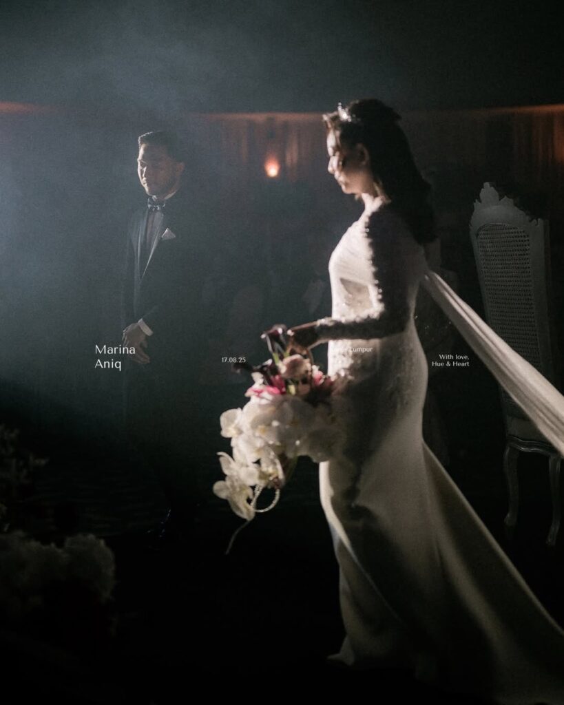 Bride holding flowers and groom standing apart in a softly lit wedding interior