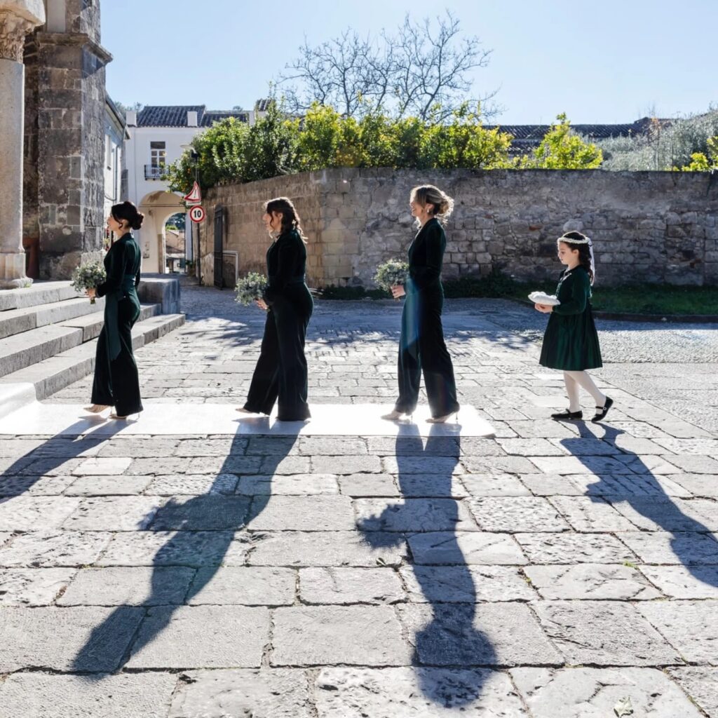 Invitados alineados al aire libre junto a la pared de una iglesia bajo el sol intenso
