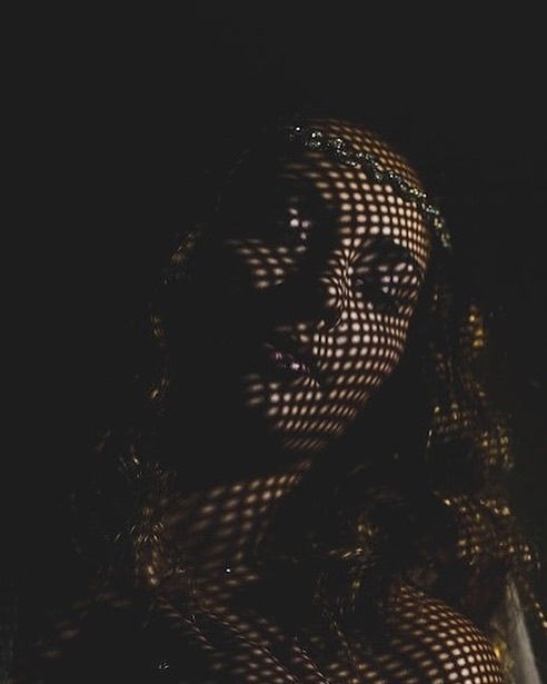 Bridal face revealed by a grid of small patches of light against darkness
