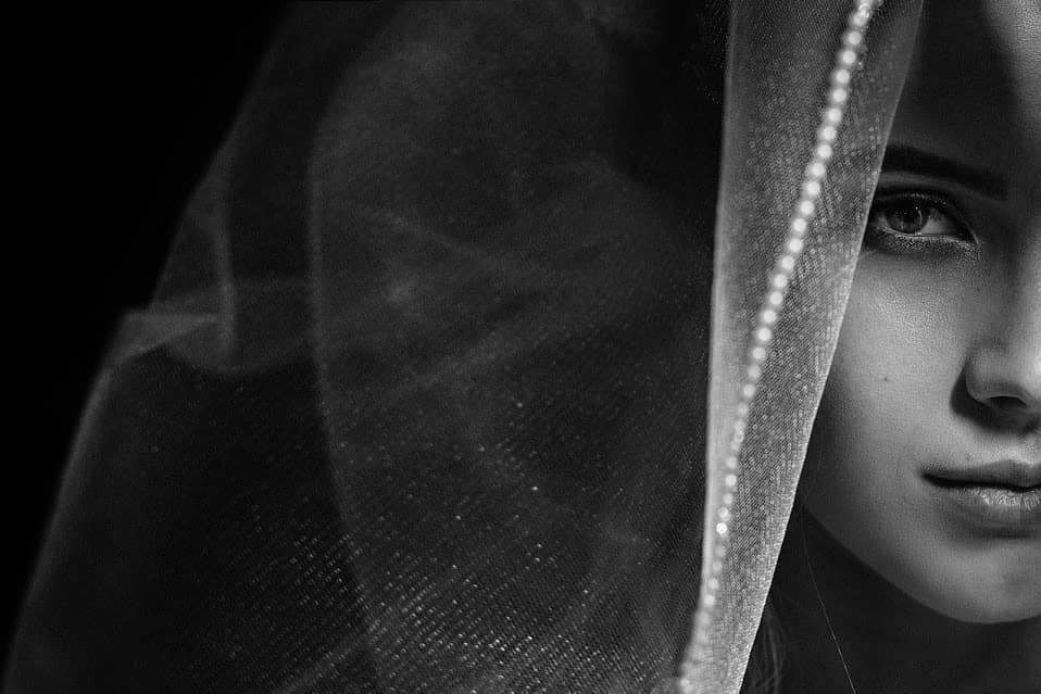 Close bridal portrait with one eye visible beside the edge of a veil
