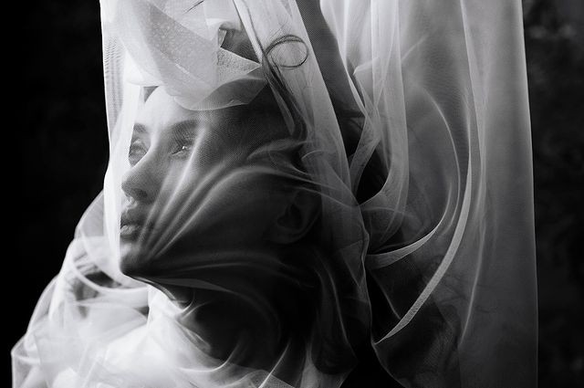 Bride's face tilted upward and wrapped in soft layers of veil