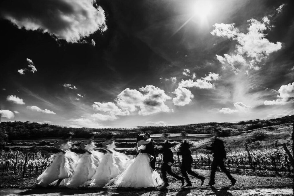 Repeated images of a walking couple beneath a dramatic monochrome sky
