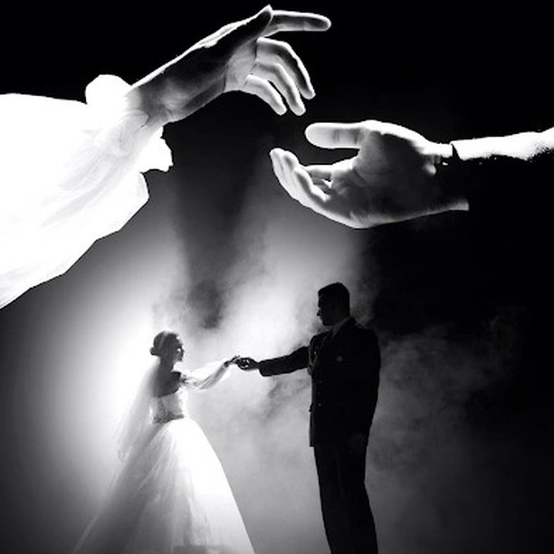 Couple holding hands beneath an enlarged image of their hands in black and white