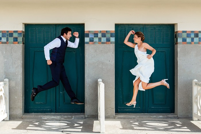 Bride and groom jumping in front of matching teal doors