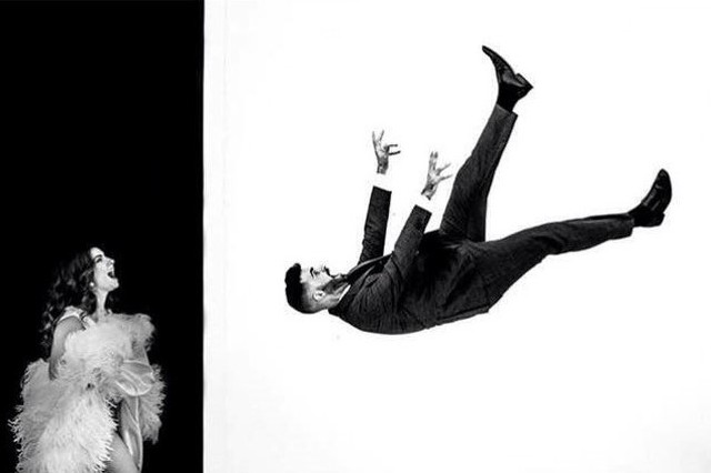 Groom suspended horizontally beside a bride against a geometric black and white wall