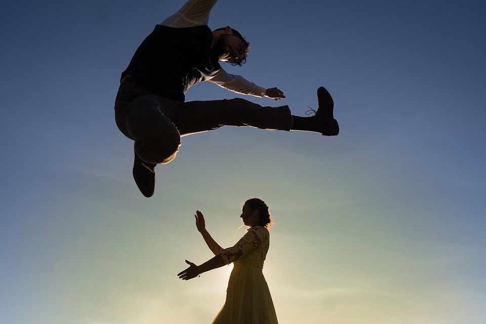 Airborne partner in the foreground above the other partner against a dusk sky