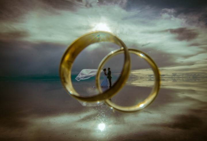 Two large rings framing a distant couple on a beach beneath a cloudy sky