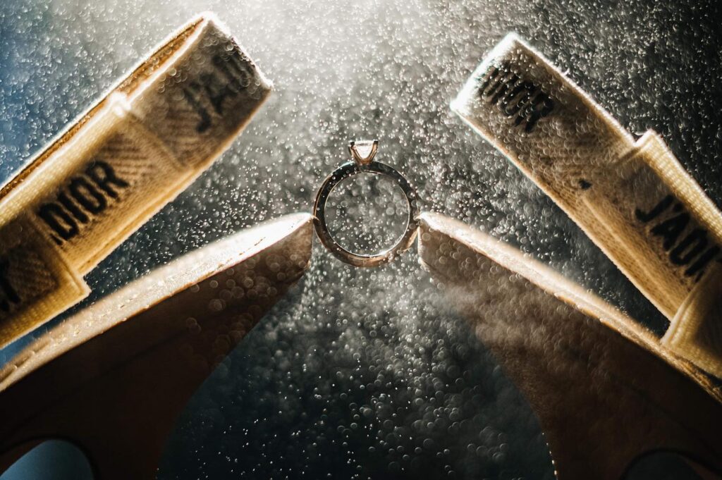 Ring suspended between wooden pieces amid sparkling droplets