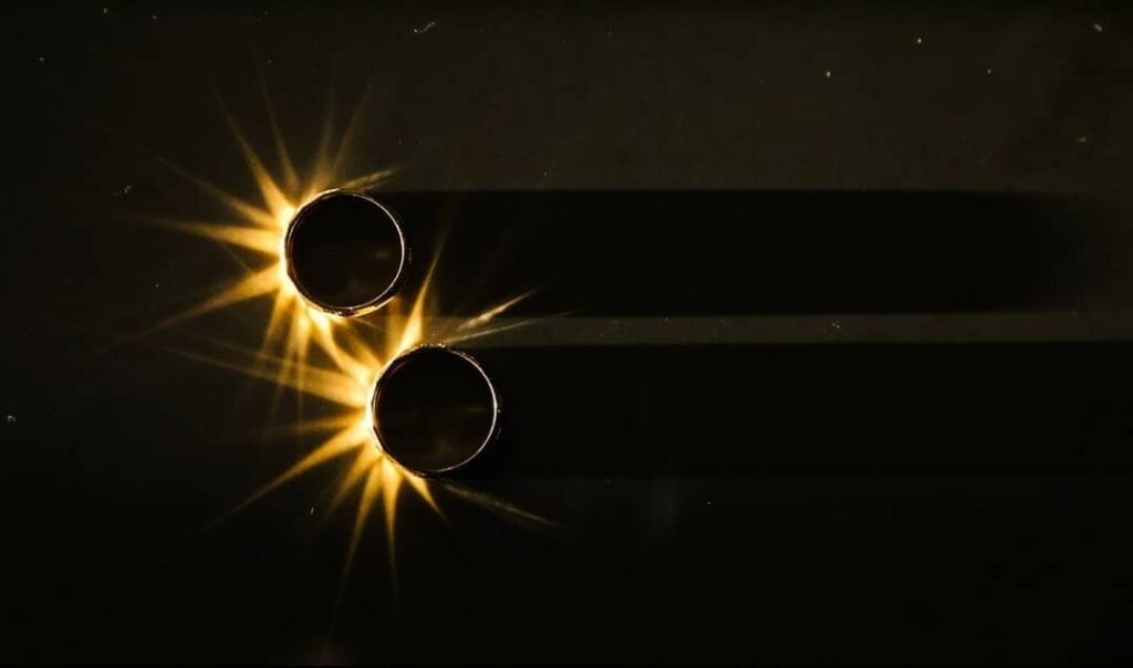 Two rings casting long shadows beside golden starbursts of light