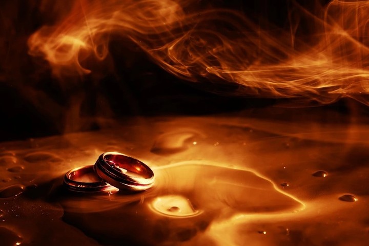Wedding rings in orange light amid swirling vapor-like shapes