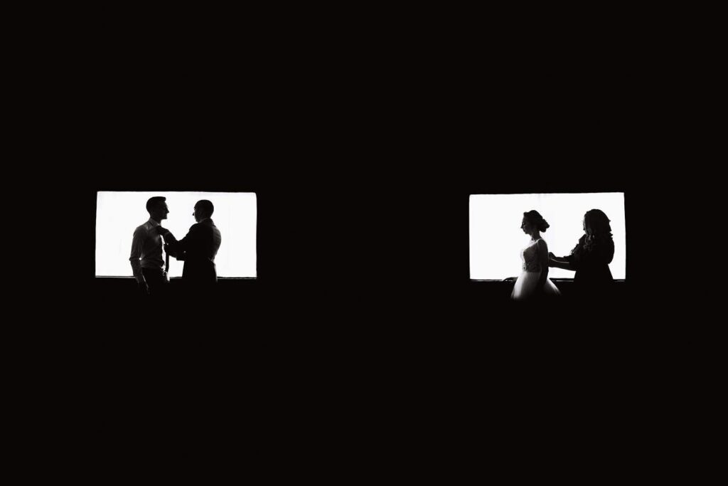 Wedding silhouettes in two bright rectangular windows against a black background