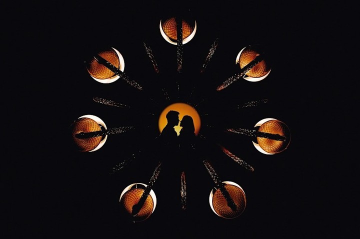 Small couple silhouette inside an orange circle surrounded by radial shapes