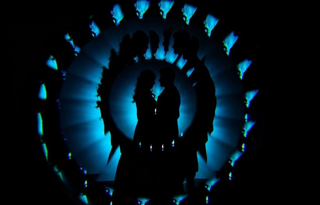 Couple silhouette repeated around a luminous blue circle