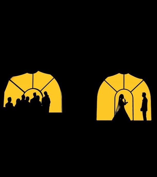Wedding guests and a couple silhouetted in two golden arched windows
