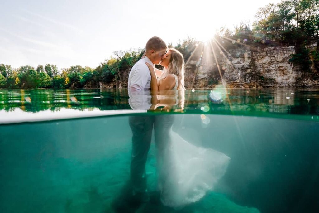 Couple kissing at the waterline with the bride's dress visible below
