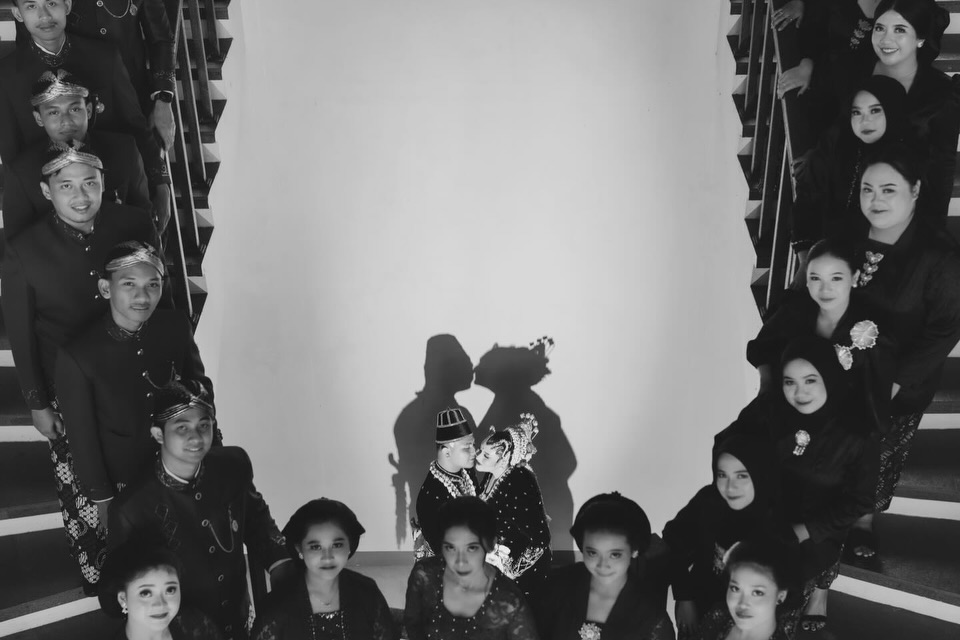 Black and white group wedding portrait arranged around a couple and their shadows