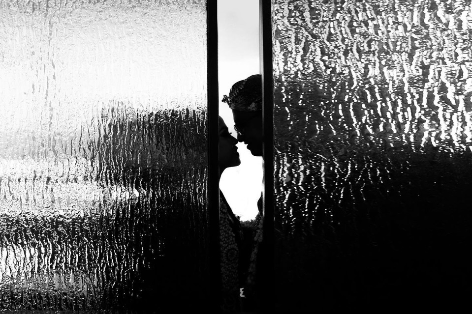 Black and white couple portrait seen through a narrow opening in textured glass