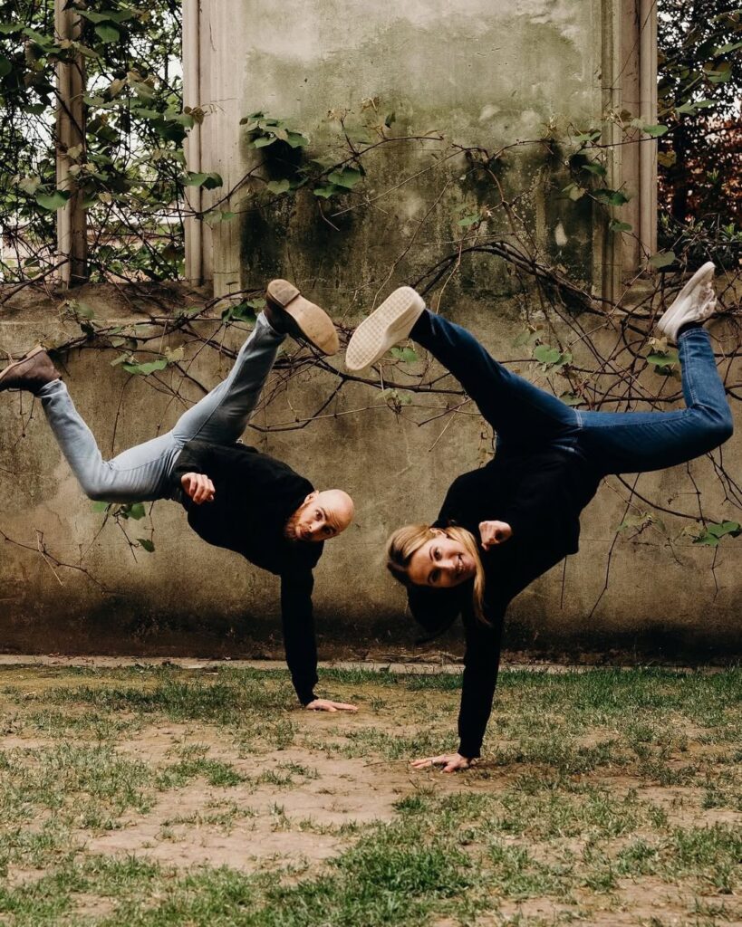 Couple doing cartwheels together on grass near stone ruins