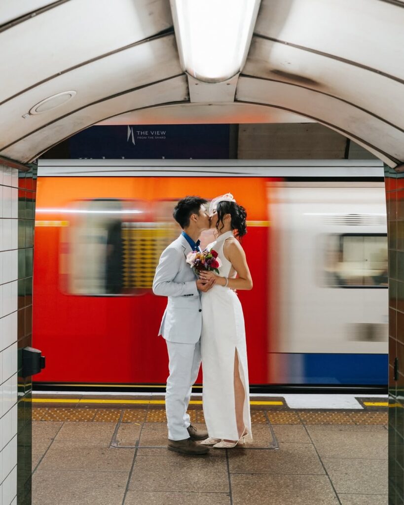 Wedding couple kissing on a London Underground platform beside a moving red train