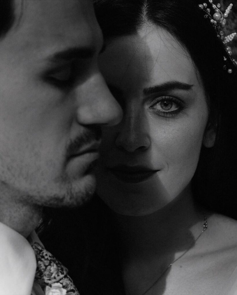 Retrato cercano en blanco y negro de una pareja, con la novia mirando hacia la cámara