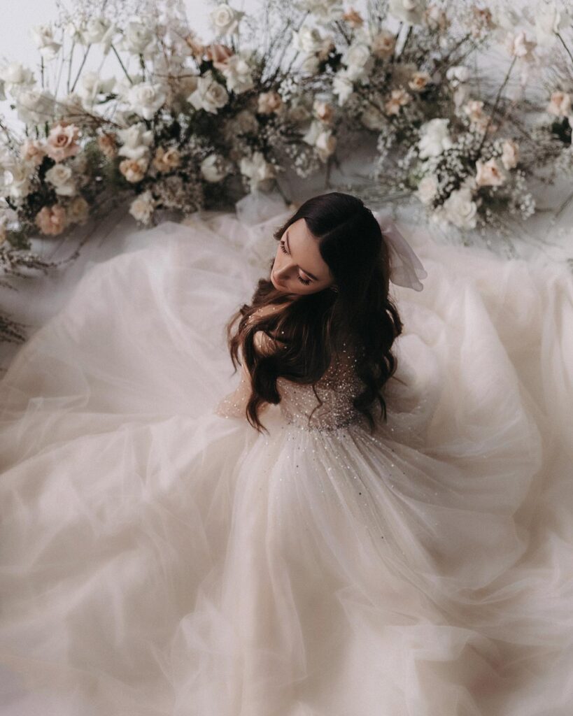 Retrato cenital de una novia rodeada por el volumen de su vestido claro y flores