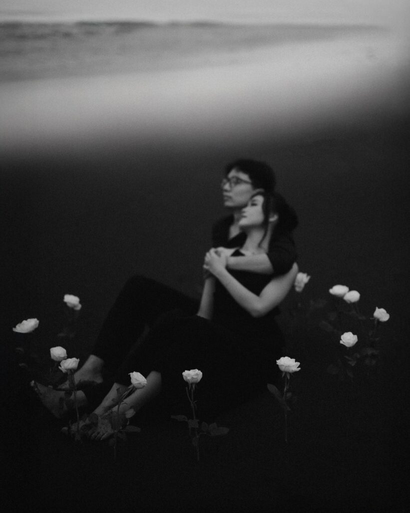 Retrato en blanco y negro de una pareja sentada y abrazada entre flores claras