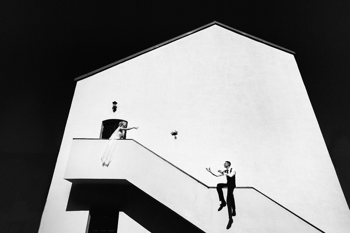 Black and white wedding portrait using a stark white building and diagonal stairway