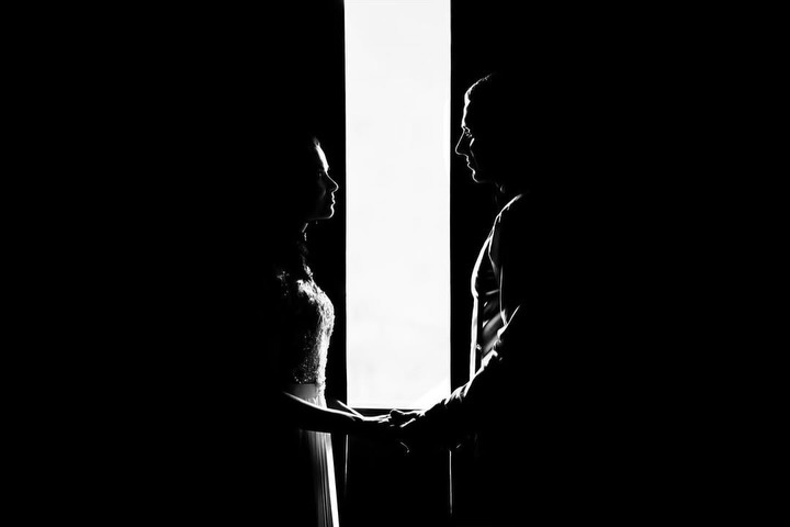 Silhouetted couple holding hands across a narrow vertical strip of light