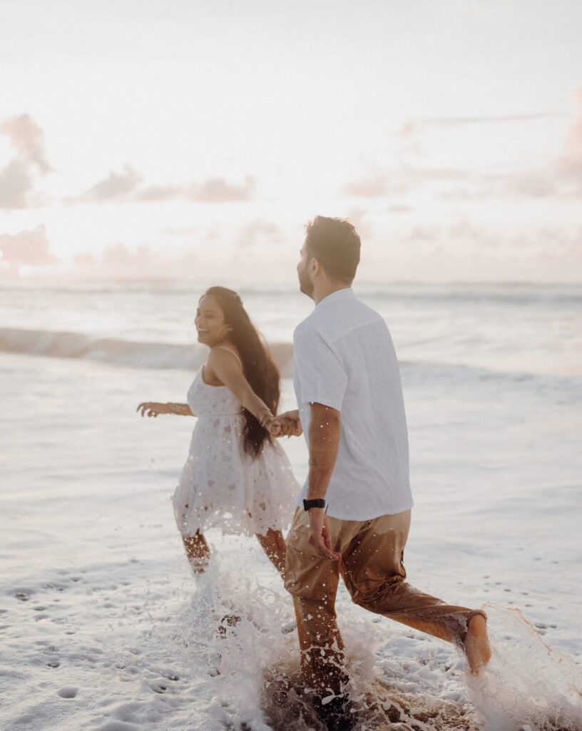 Couple running hand in hand through shallow surf at the beach