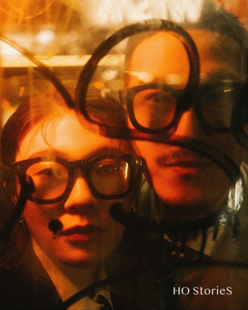 Playful close portrait of a couple in glasses behind dark looping lines