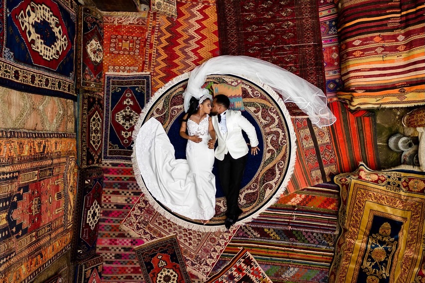 Overhead portrait of a wedding couple surrounded by colourful patterned rugs