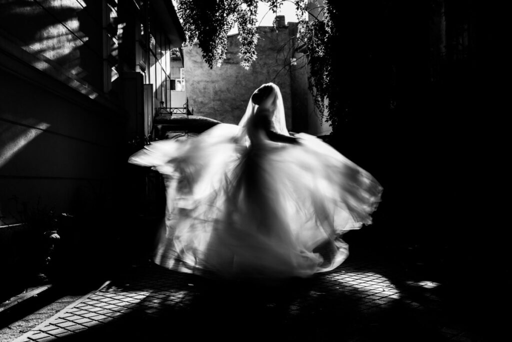 Novia girando con la tela en movimiento en un pasaje iluminado, en blanco y negro