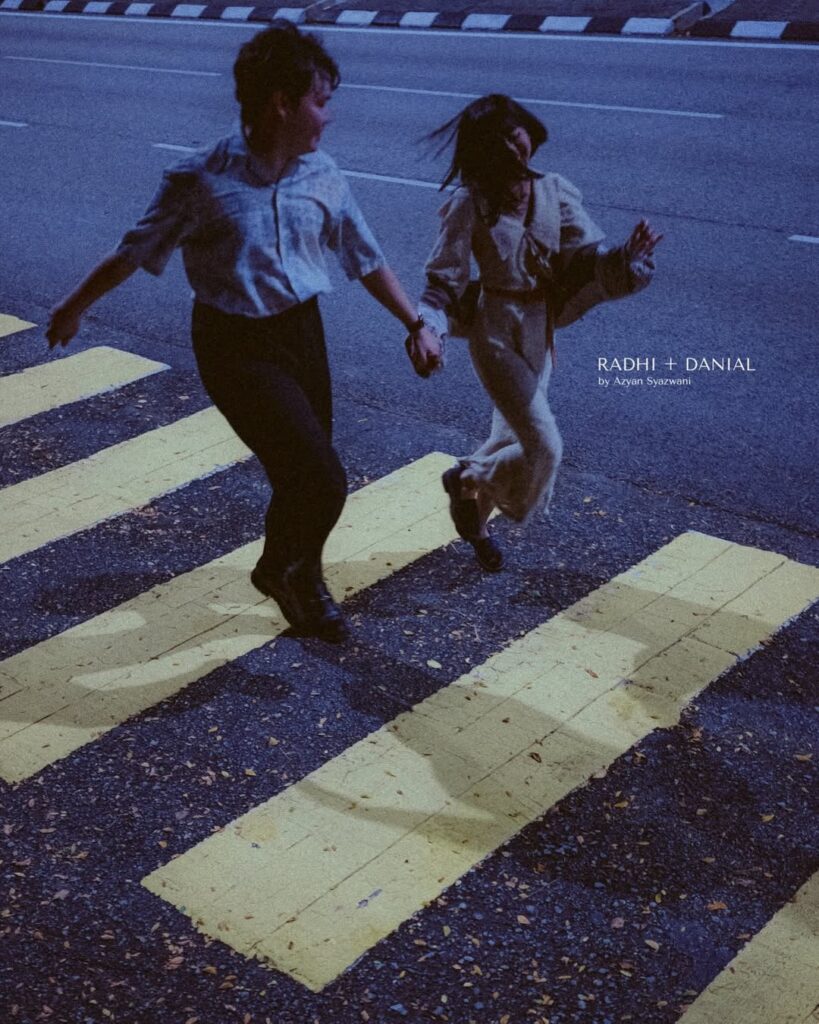 Pareja de la mano cruzando un paso de peatones bajo una luz azul al atardecer