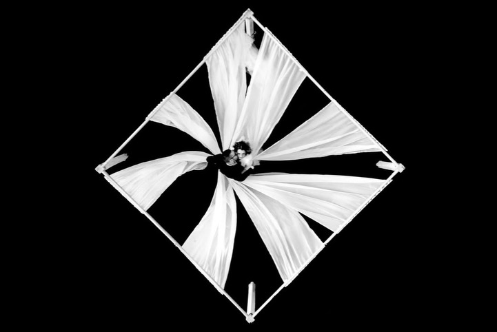 Retrato en blanco y negro de una pareja en el centro de una estructura de tela blanca en forma de rombo