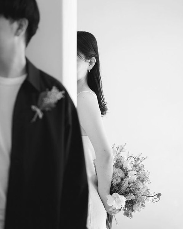 Retrato en blanco y negro de unos novios separados por el borde de una pared