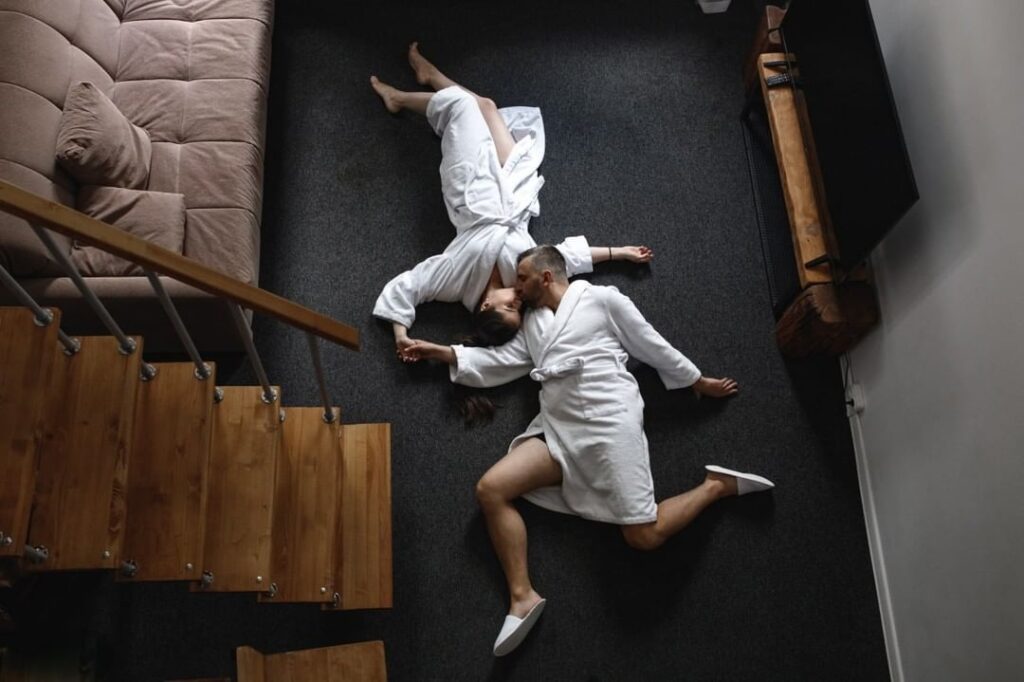 Una pareja con batas blancas fotografiada desde arriba en una habitación con alfombra oscura
