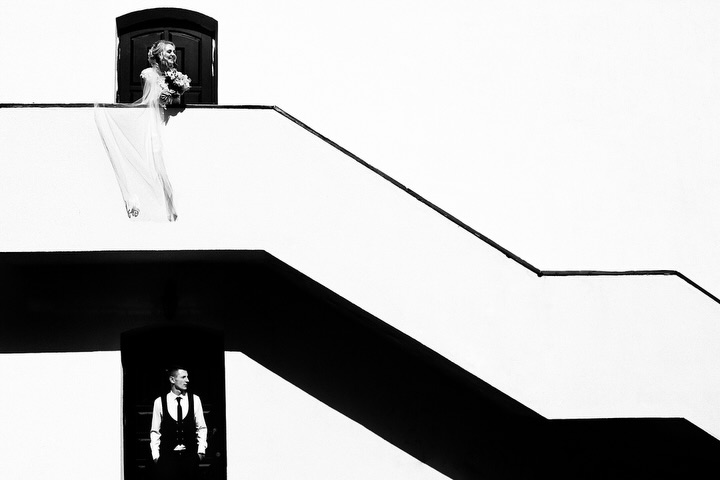 Novia arriba y novio abajo de una escalera diagonal en blanco y negro