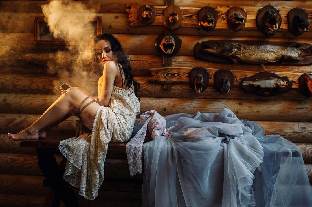 Novia sentada en un interior de madera junto a una nube luminosa cálida y tela azul