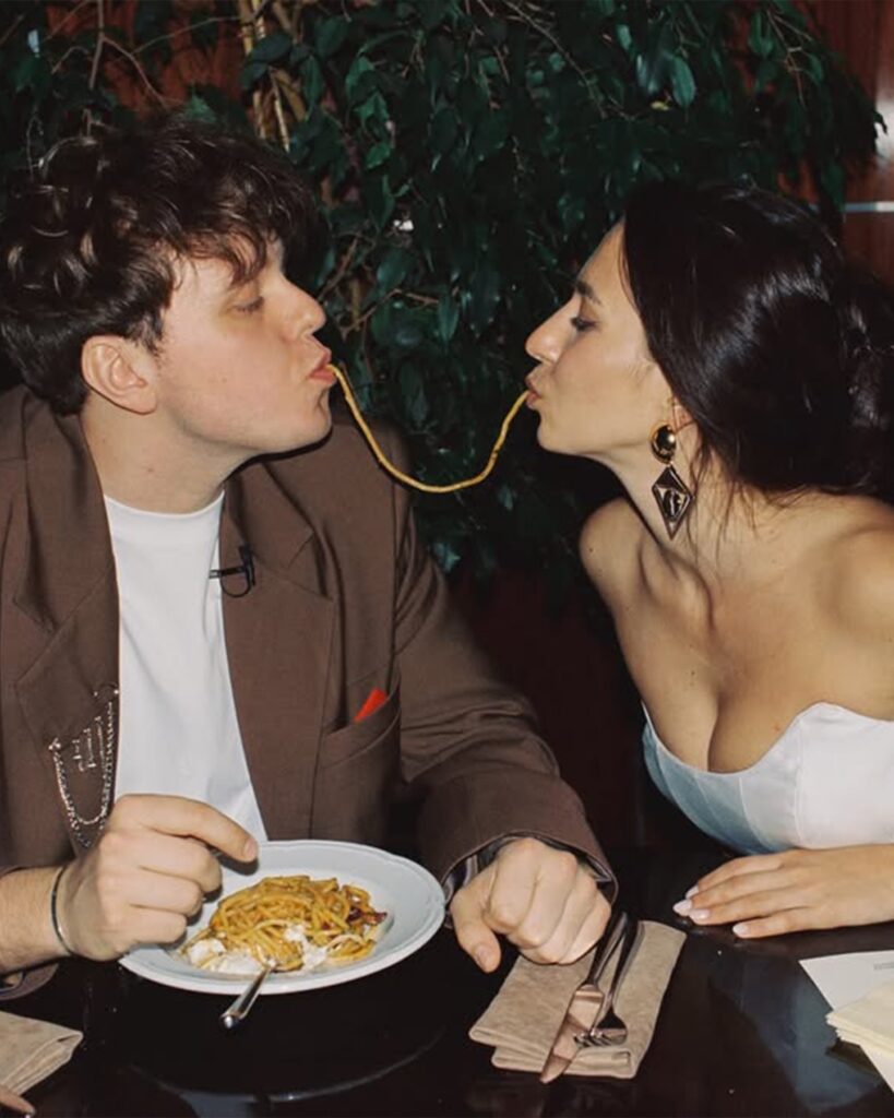 Couple sharing a strand of pasta across a restaurant table