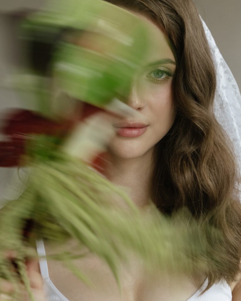 Bridal face surrounded by a blurred green and orange bouquet