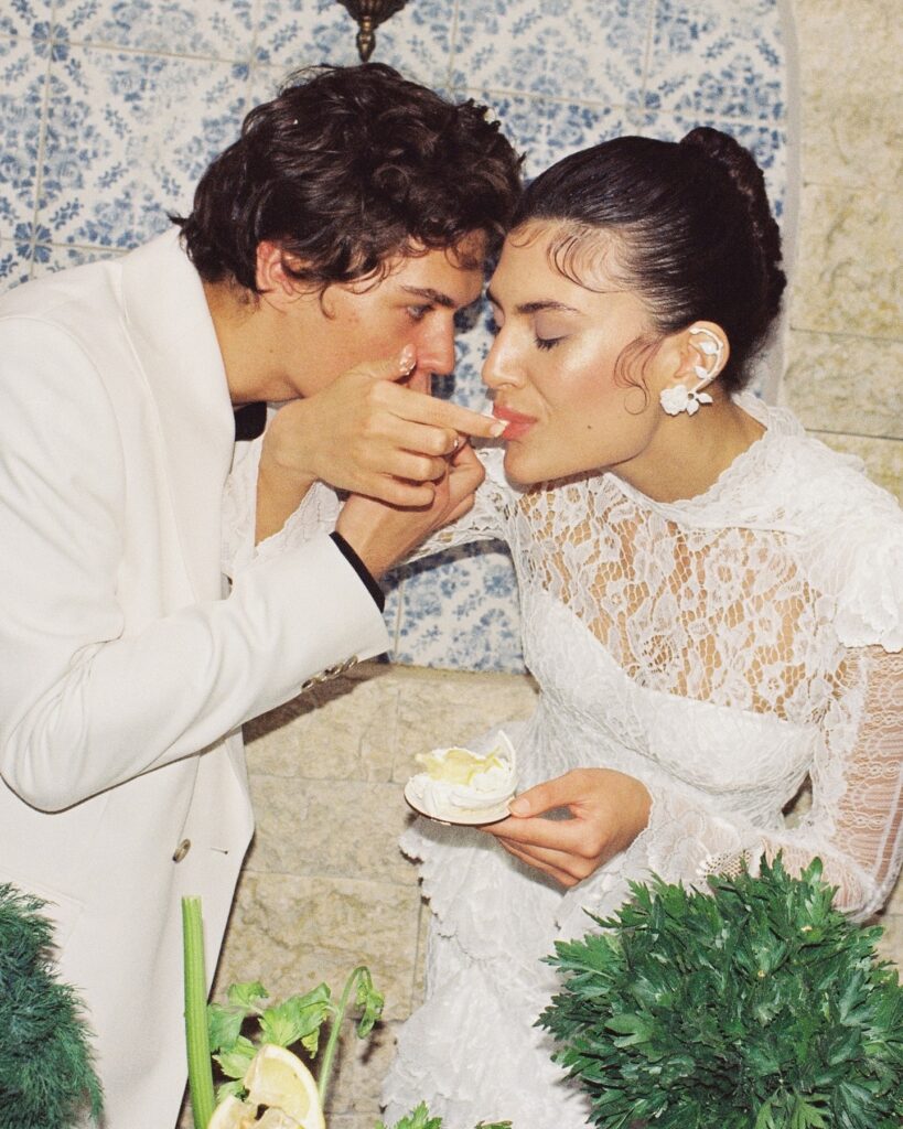 Couple sharing dessert outdoors beside a blue and white wall