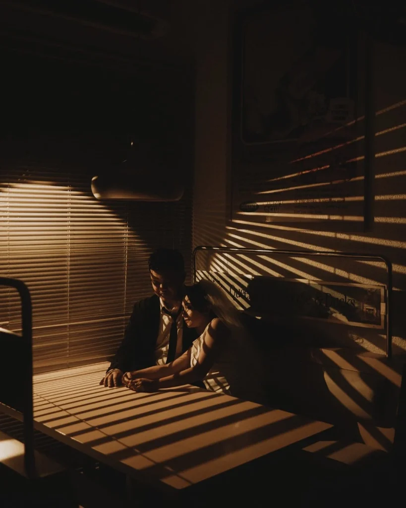 Couple seated in striped light cast across a dark room
