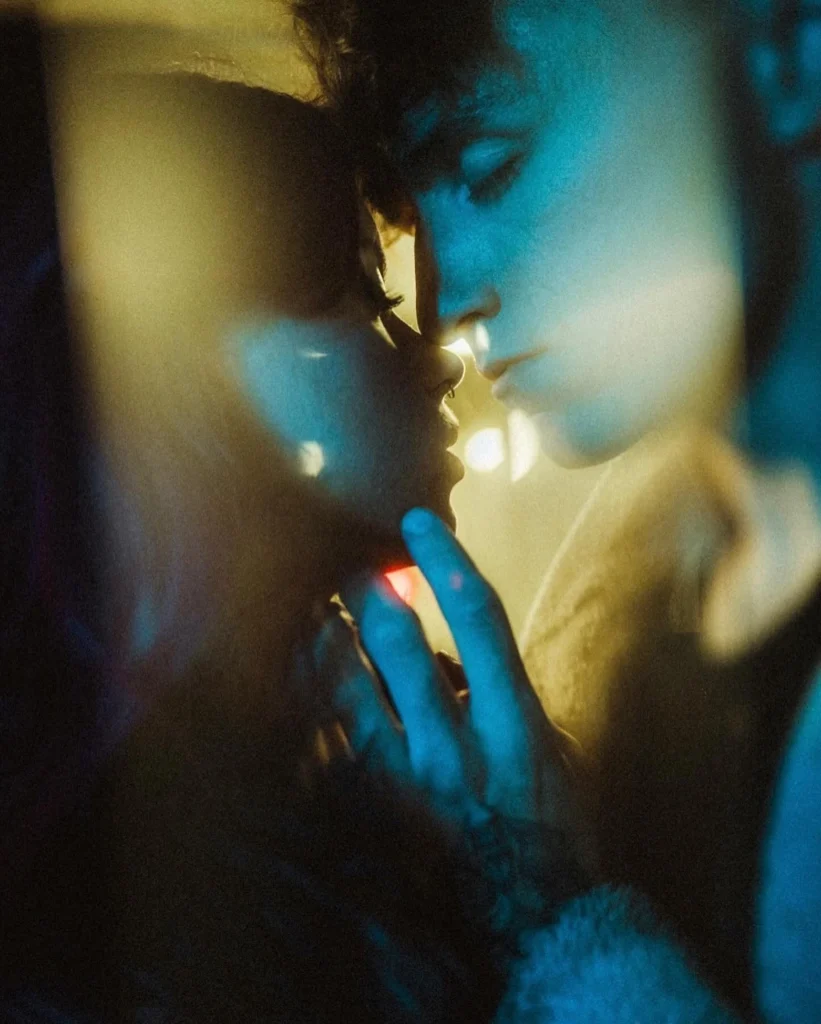 Close couple portrait with hands near their faces and blue light across the frame