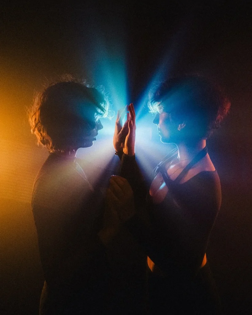 Couple touching raised palms in contrasting blue and amber light