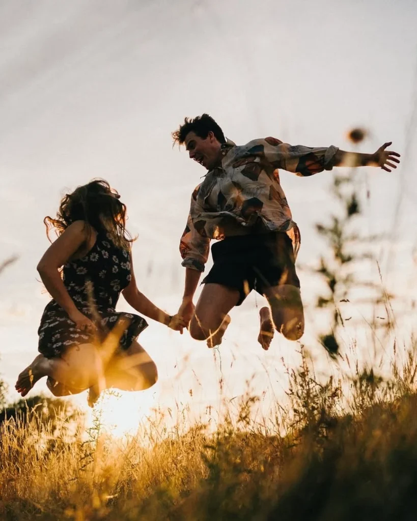 Couple in casual clothes jumping above sunlit grass